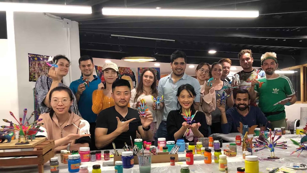 A group of people in an art studio with paint bottles and brushes on tables. 5