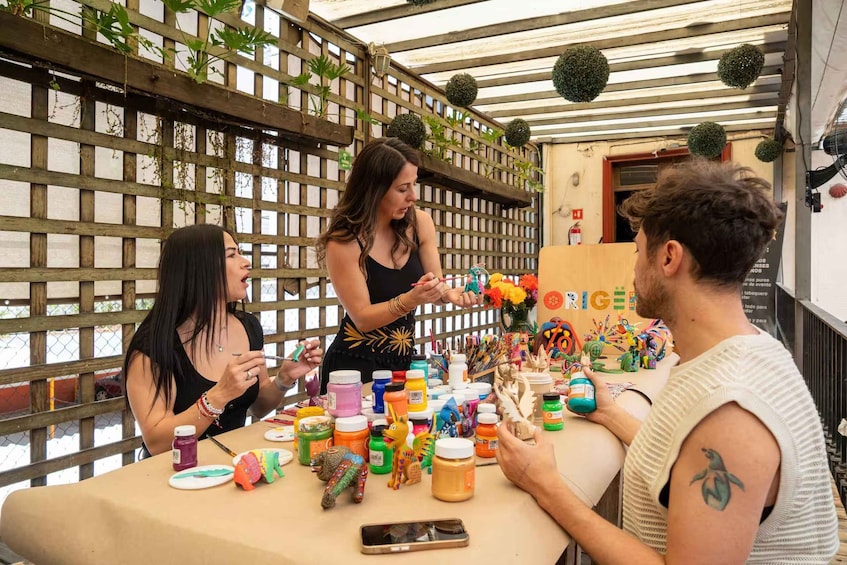 A group of people at a table with art supplies and a sign that reads 'ORIGEN.' 4