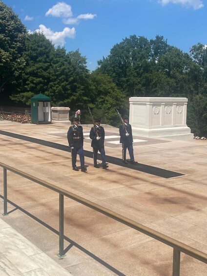 A memorial with three uniformed guards standing at attention. 4