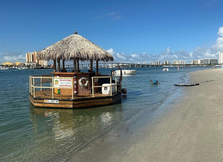 A boat with a thatched roof docked at a beach, a lifebuoy, and a sign with contact information. 3