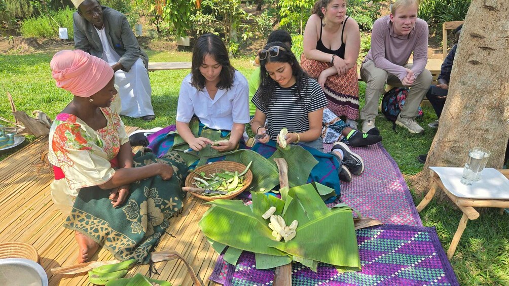 A group of people outdoors, engaged in a food preparation activity using banana leaves. 1