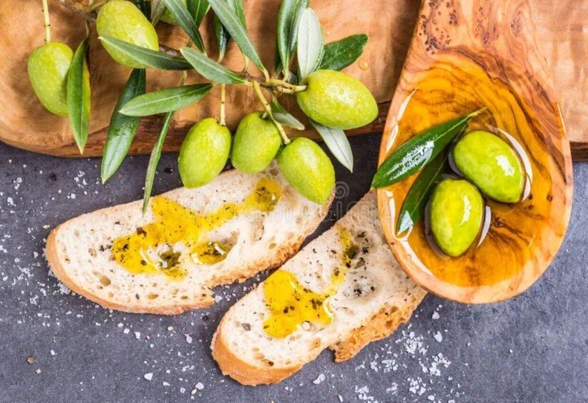 Sliced bread with olive oil and green olives on a wooden board. 1