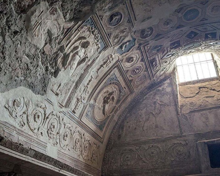 An interior with detailed frescoes and a window allowing natural light. 4