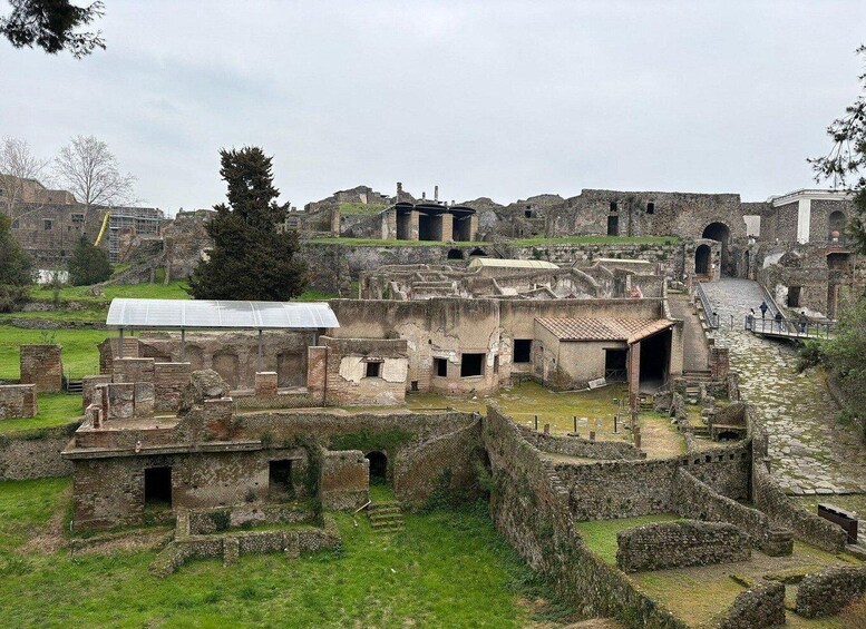 Ancient ruins with stone structures, a covered walkway, and a large tree. 1