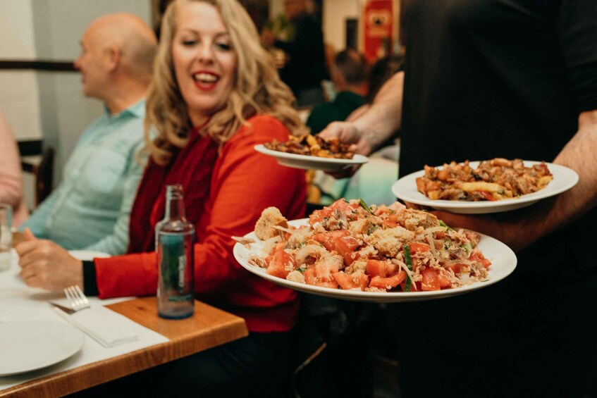 A person holding a plate of food at a dining table. 1
