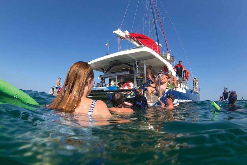 People swimming and a boat with a red canopy in the ocean. 1