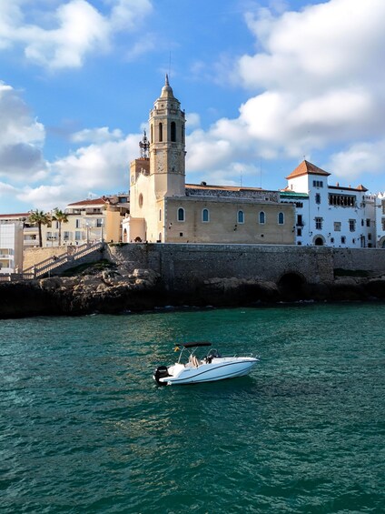 A coastal town with a prominent tower, a white building with a red roof, and a small boat on the water. 5
