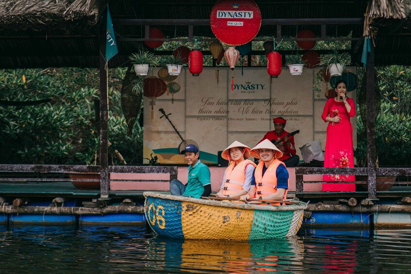 A traditional boat with people wearing conical hats, a woman in a red dress, and a sign with 'DYNASTY' and Vietnamese text. 5