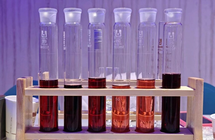 A wooden rack holding several test tubes with colored liquids, some with measurement markings. 5