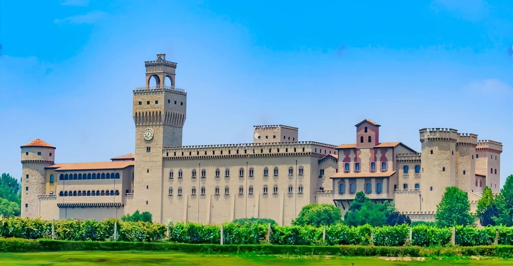 A large castle with multiple towers and a clock tower, surrounded by lush greenery. 1