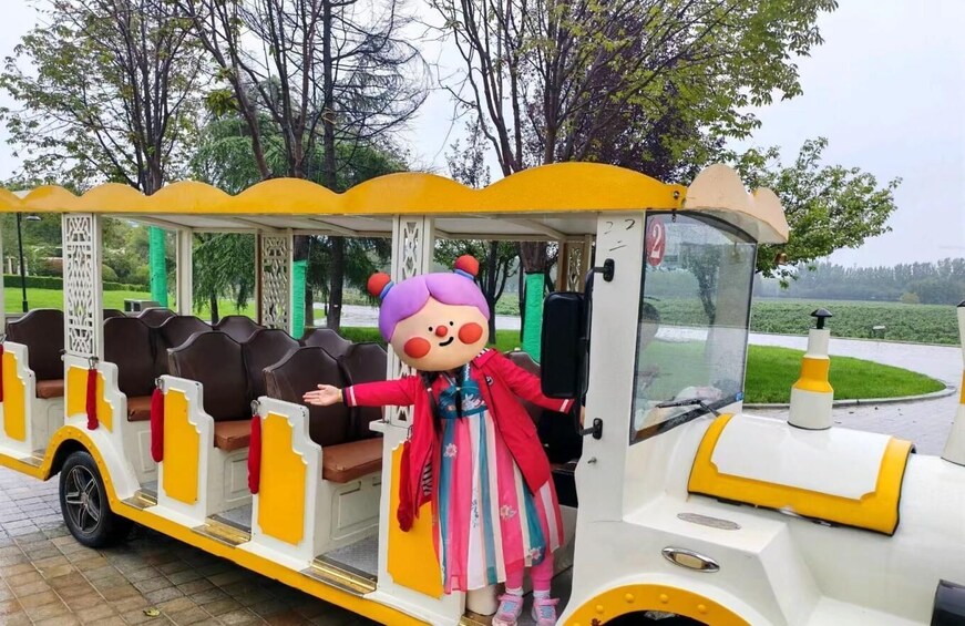 A yellow and white train with a character in a red coat standing at the door. 2