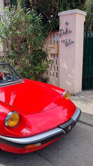 A red vintage car parked in front of a building with a sign that reads 'Dolce Vita.' 5
