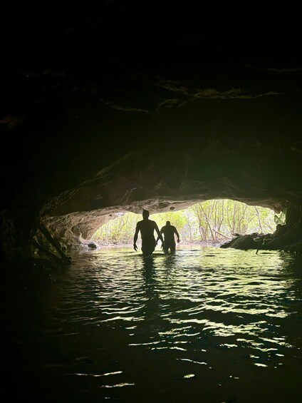 Two people walking through a cave with water at the bottom. 1