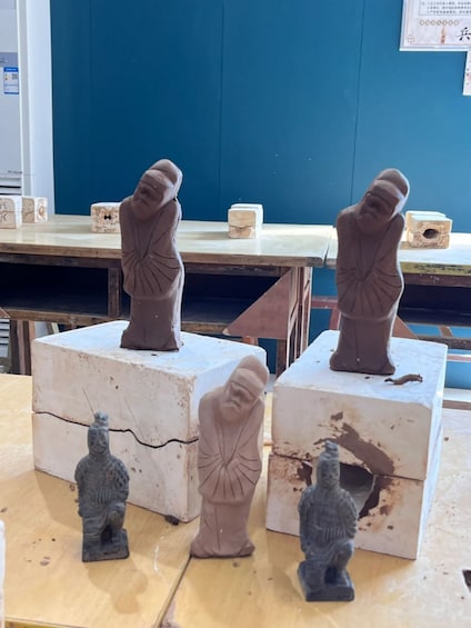 Three statues on white pedestals in a workshop. 3