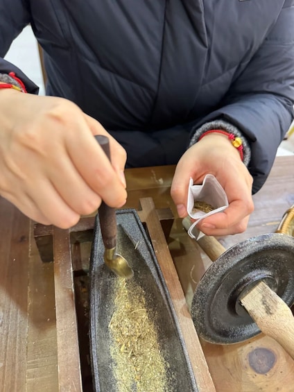 A person using a mortar and pestle to grind a substance. 2