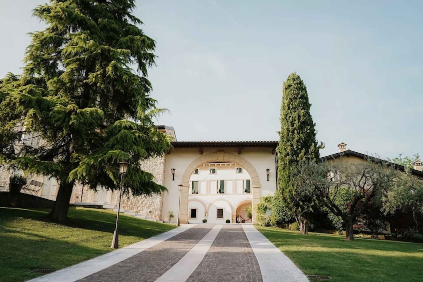 A building with an arched entrance, a pathway leading to it, and surrounding greenery. 4