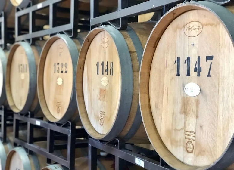 Wooden wine barrels with numbers 1322, 1148, and 1147 on a metal rack. 2