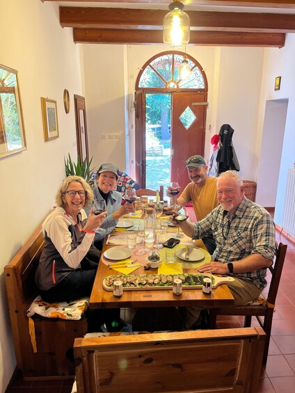 A group of people dining at a wooden table with a variety of dishes and drinks. 4