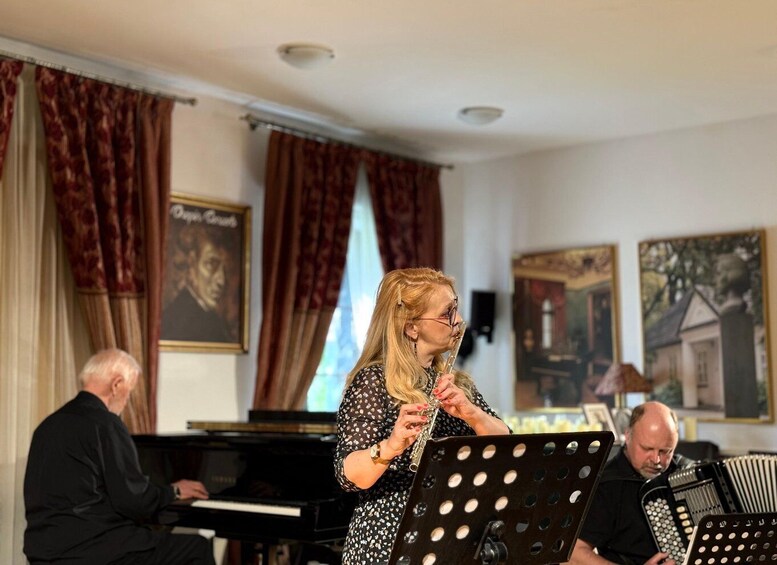 A woman playing a flute in a room with a piano and accordion in the background. 3