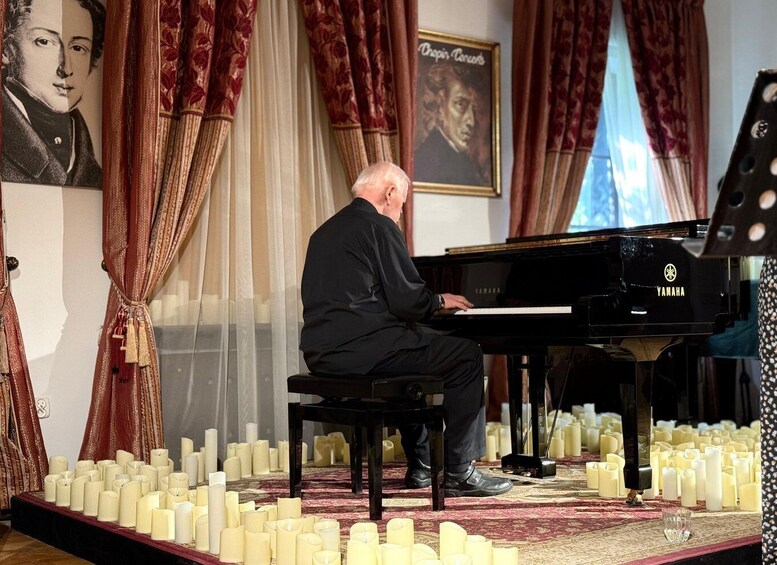 A man playing a Yamaha grand piano surrounded by candles. 4