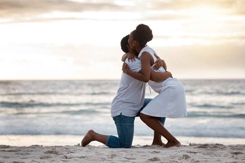 Two people embracing on a beach with the ocean in the background. 5