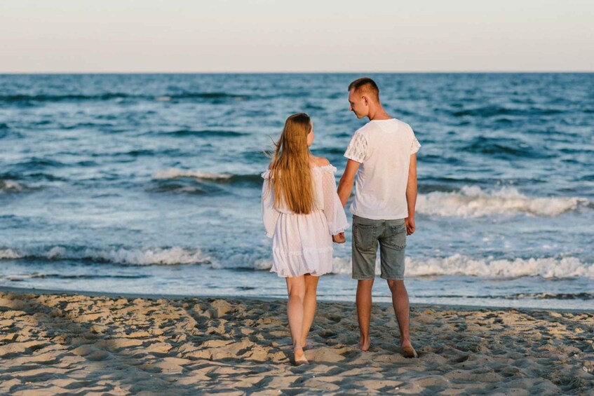 A couple standing on a rocky beach with the ocean in the background. 3