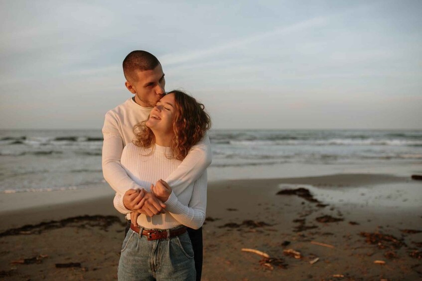 A couple embracing on a beach with the ocean in the background. 1