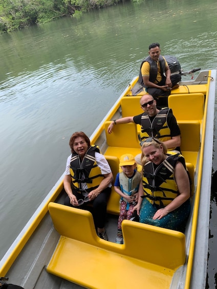 A group of people on a yellow boat with life jackets, floating on calm water. 4