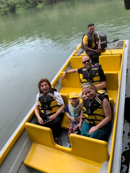 A group of people on a yellow boat with life jackets, floating on calm water. 5