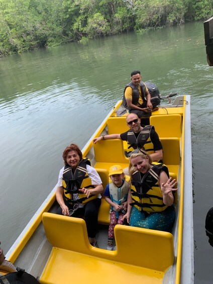 A group of people in a yellow boat on a calm river surrounded by greenery. 2