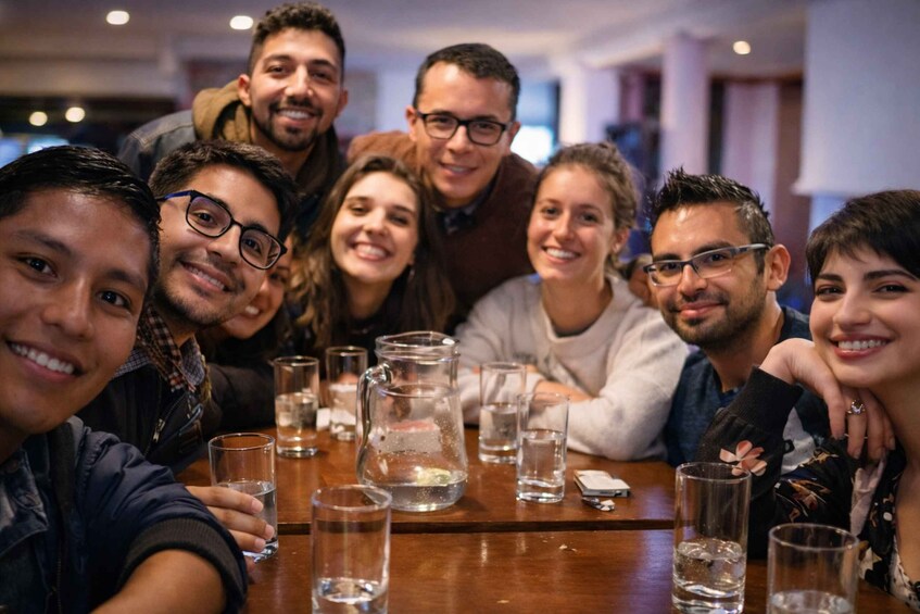 A group of people sitting around a table with glasses of water and a pitcher. 1