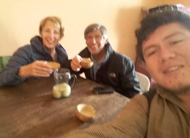 Three people sitting at a table with food and a pitcher. 2