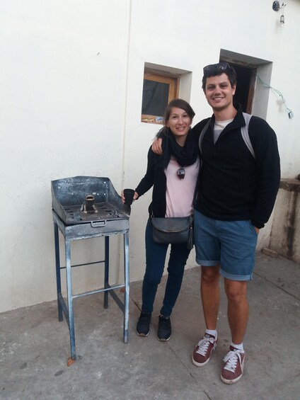 Two people standing next to a portable grill outdoors. 4
