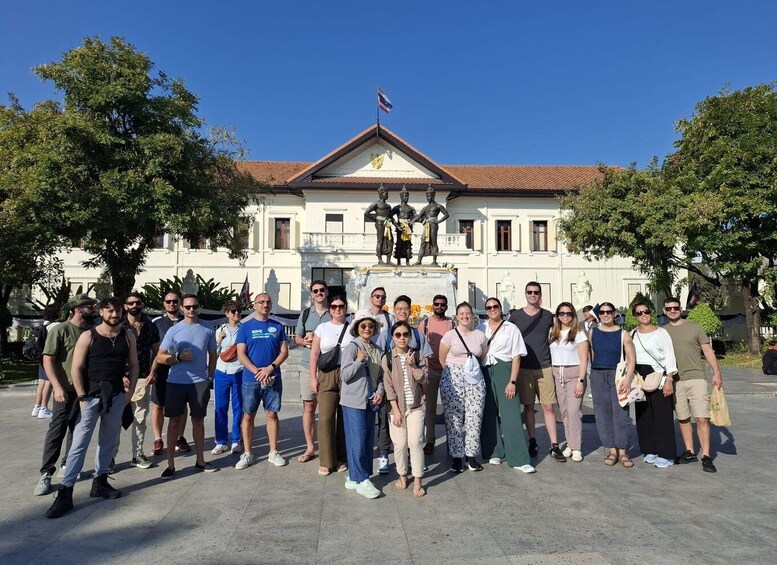 A group of people standing in front of a building with a statue and a flag. 1