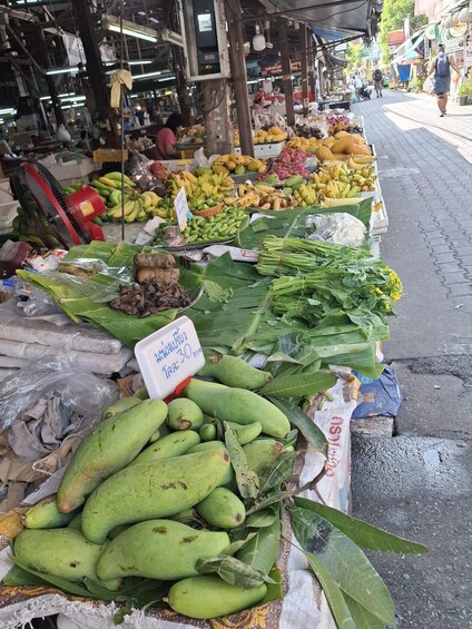 A market stall with various fruits and vegetables, including bananas, mangoes, and leafy greens. 4