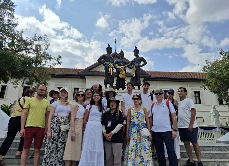 A group of people posing in front of a historical monument with a flag. 2