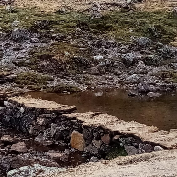 A rocky stream with moss-covered stones and a small pond. 2