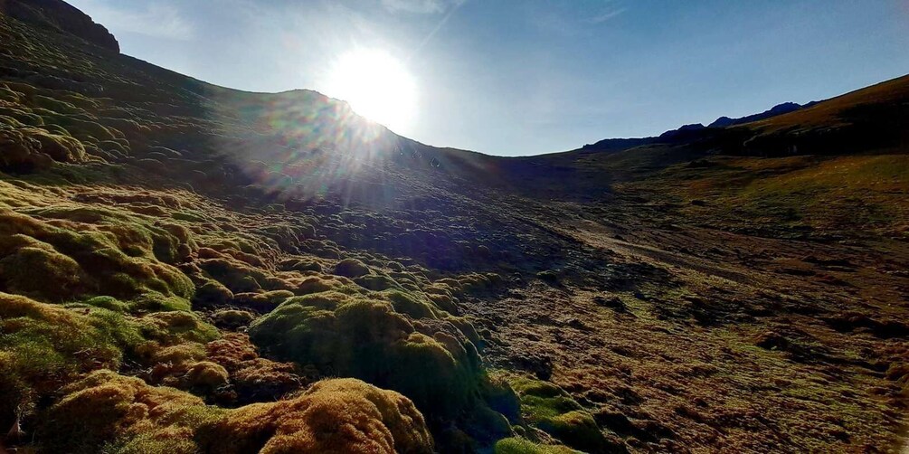 A sunlit valley with rugged terrain and sparse vegetation. 5