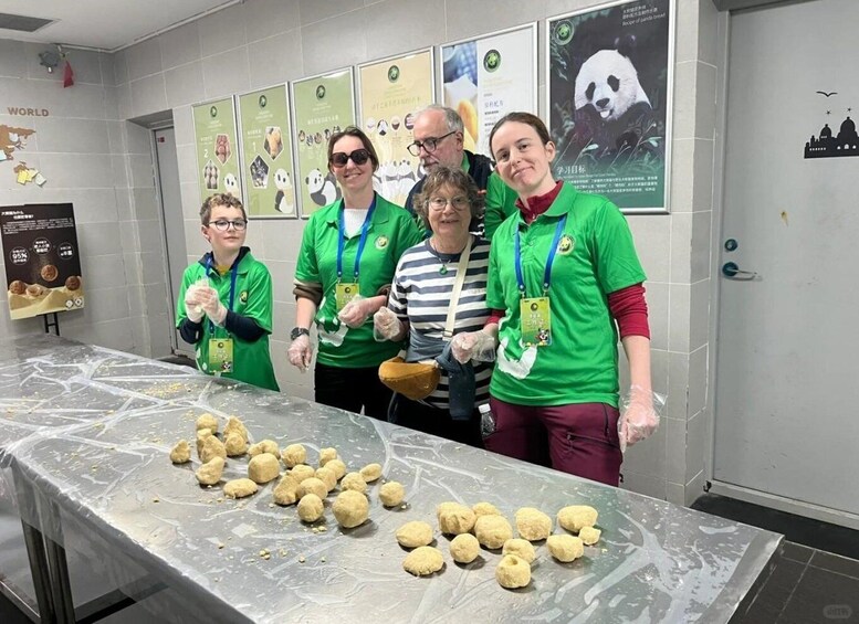 A group of people in green shirts with lanyards standing in front of a table with dough balls. 4