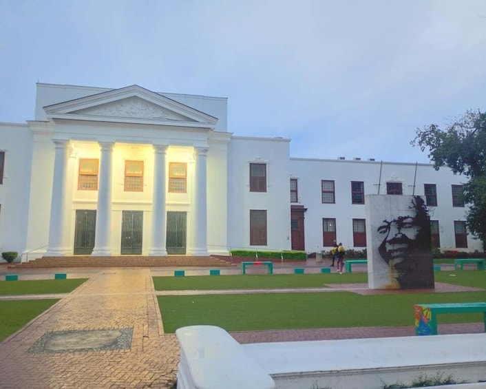 A white building with columns and a statue in the foreground. 1