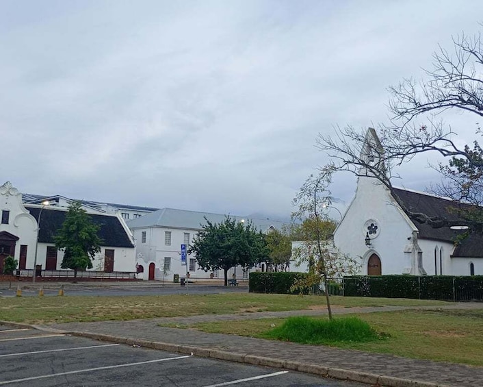 A church with a steeple, a parking lot, and a grassy area with trees. 3