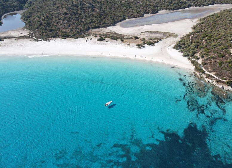 A coastal area with clear turquoise waters, a sandy beach, and a boat floating near the shore. 2