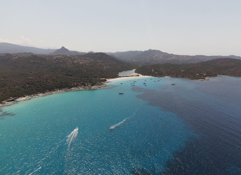 A coastal landscape with clear turquoise waters, boats, and a mountainous backdrop. 3