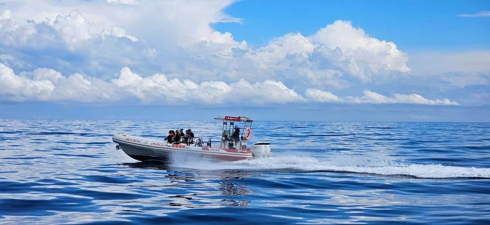 A boat with passengers on a calm sea under a partly cloudy sky. 1