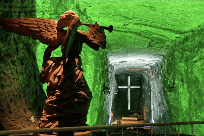 A statue of an angel with wings and a trumpet in a tunnel with green walls. 3