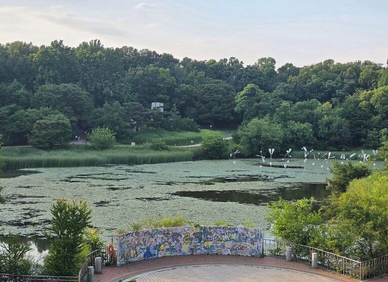 Un parque con un estanque, esculturas de cisnes y un mural en una pared curva. 5