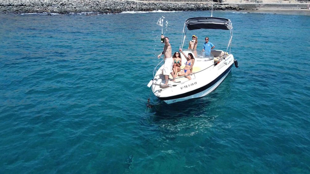 A boat with people on it, a rocky shoreline, and calm blue water. 2