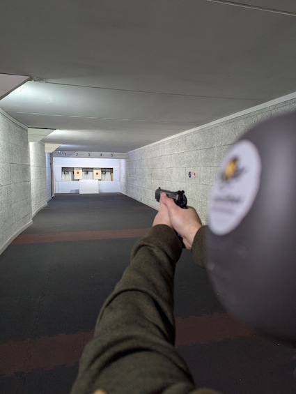 A person aiming a handgun at a shooting range with numbered targets. 2