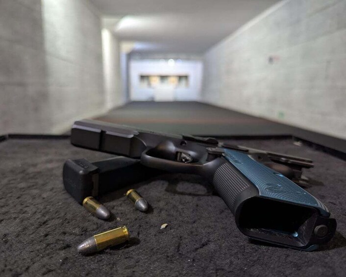 A handgun with bullets on a carpeted floor in a dimly lit hallway. 5