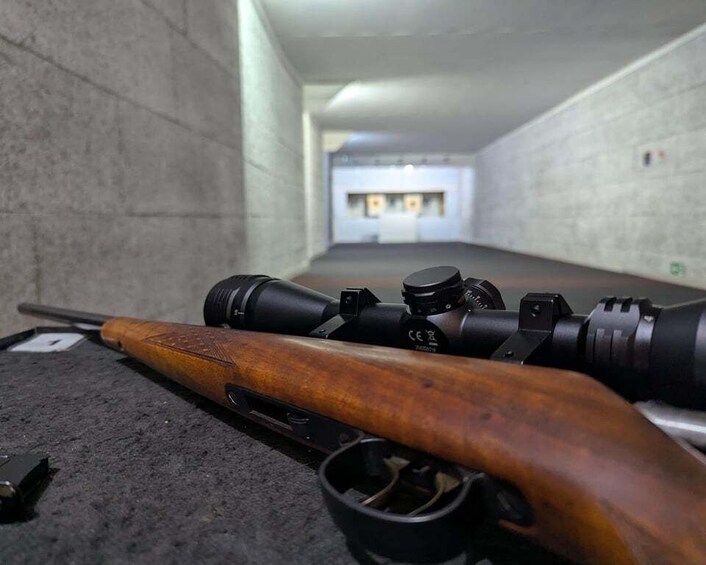 A rifle with a scope lying on a carpeted floor in a hallway. 4